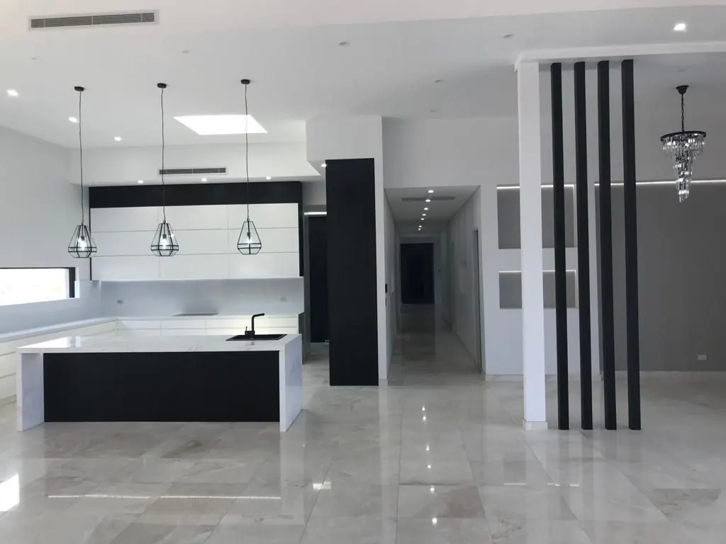 White kitchen with stone island and pendant lights